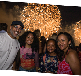 Four people pose for a photo in front of fireworks 