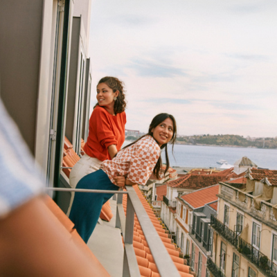 Two women on a balcony over looking a city street 
